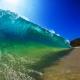 en våg håller på att slå över intill en solig strand.jpg