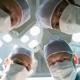 fyra läkare i en operationssal står lutade ner och tittar in i kameran.jpg
