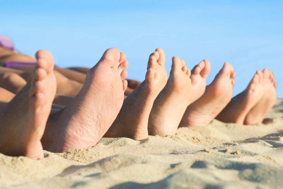tre par fötter på en strand.jpg