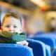 pojke sitter bakomfram på ett säte och tittar bakåt på ett tåg.jpg