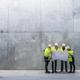 fyra byggpersoner står och kollar på den ritning i ett stort betongrum.jpg