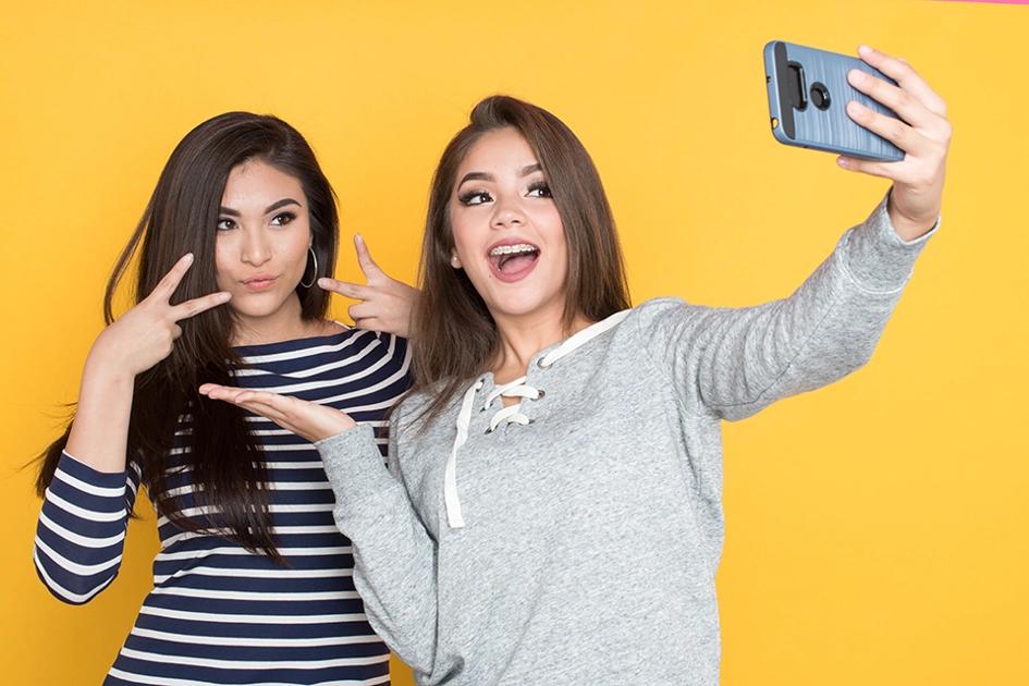Två Tjejer Posear För En Selfie Mot Gul Bakgrund